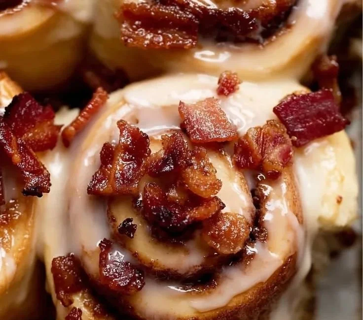 Delicious Bourbon Maple Bacon Cinnamon Rolls topped with syrup and crispy bacon