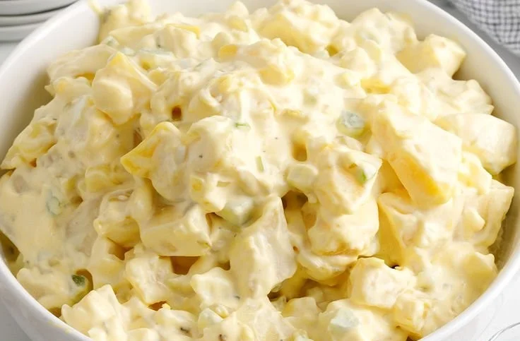 Bowl of creamy potato salad garnished with herbs and spices.