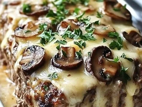 Delicious Mushroom Swiss Cheese Meatloaf topped with sautéed mushrooms and melted cheese.